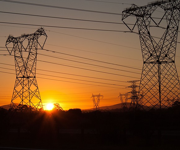 High-voltage transmission line lattice towers at sunset